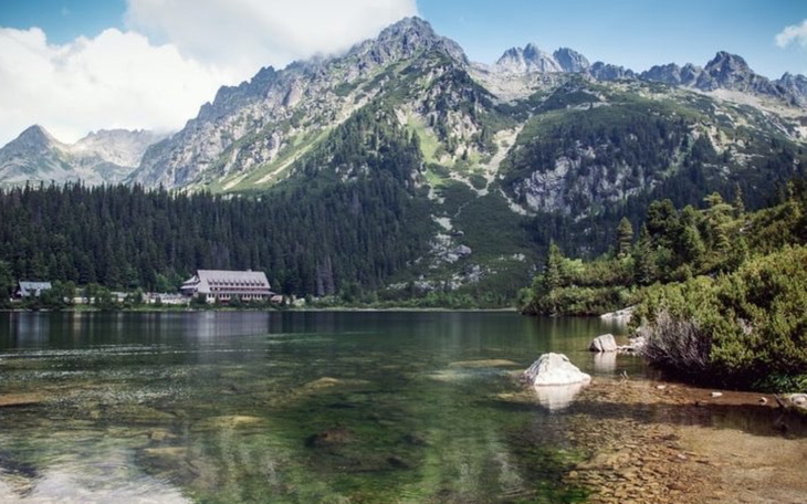 Górski krajobraz z jeziorem i zielonymi drzewami.