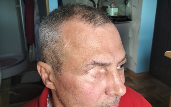 Mężczyzna z krótkimi włosami patrzy w bok, w tle kuchnia.