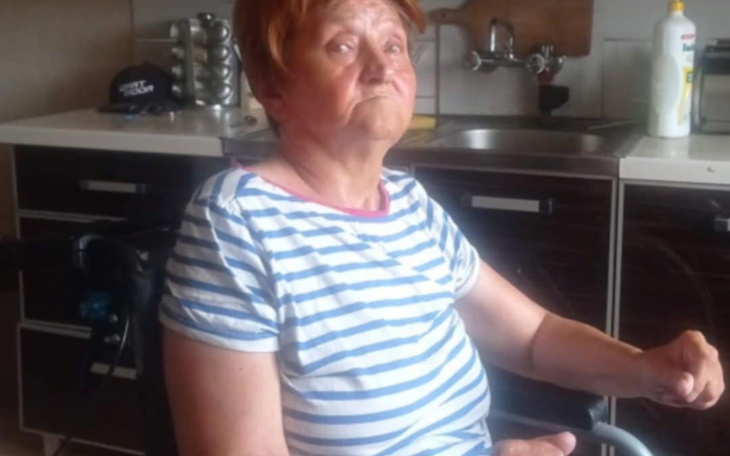 Starsza kobieta w wózku inwalidzkim, z wyrazem twarzy pełnym emocji.