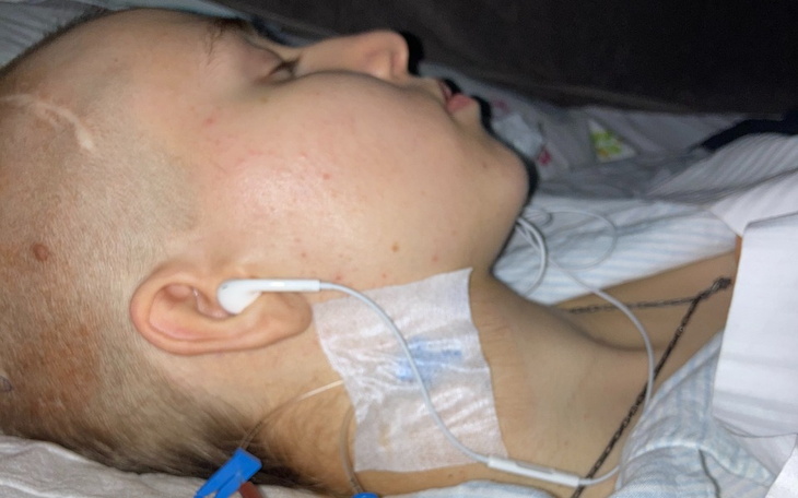 Młoda osoba leżąca w łóżku, z opaską na szyi.