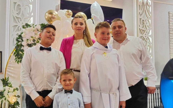 Rodzina na uroczystości, uśmiechnięte dzieci w eleganckich strojach.