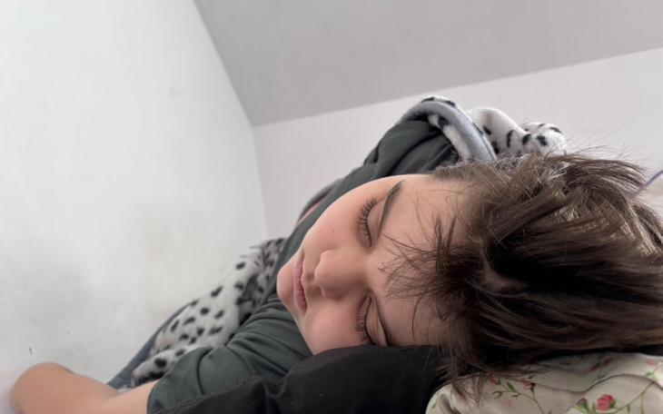 Chłopiec śpiący na poduszce w jasnym pokoju.