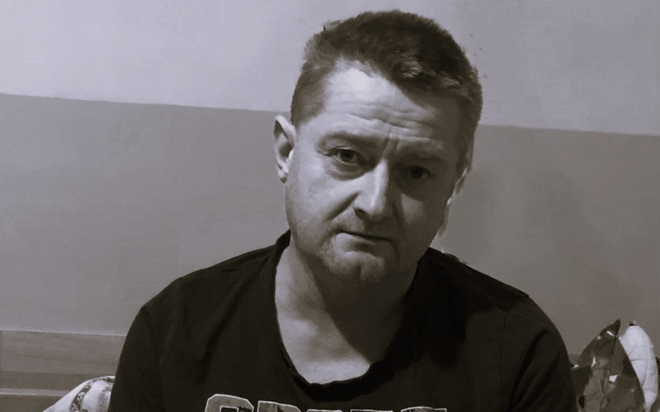 Człowiek w czarnej koszulce, siedzący w pokoju.