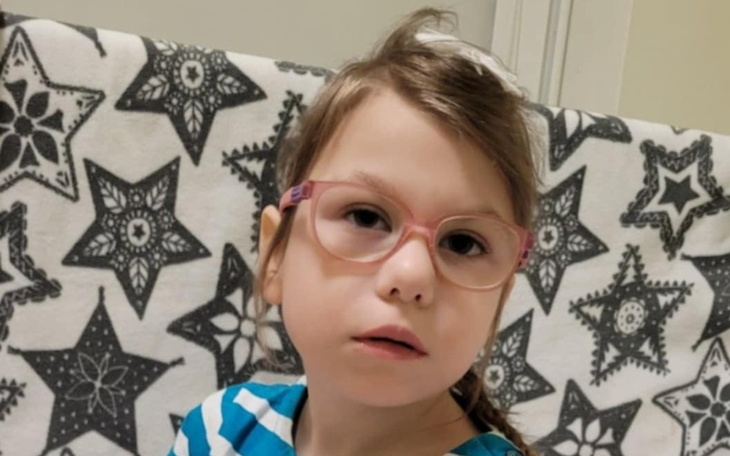 Dziewczynka w okularach na tle wzorzystego koca.