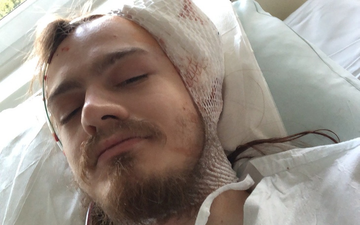 Młody mężczyzna w szpitalu, z opatrunkiem na głowie.