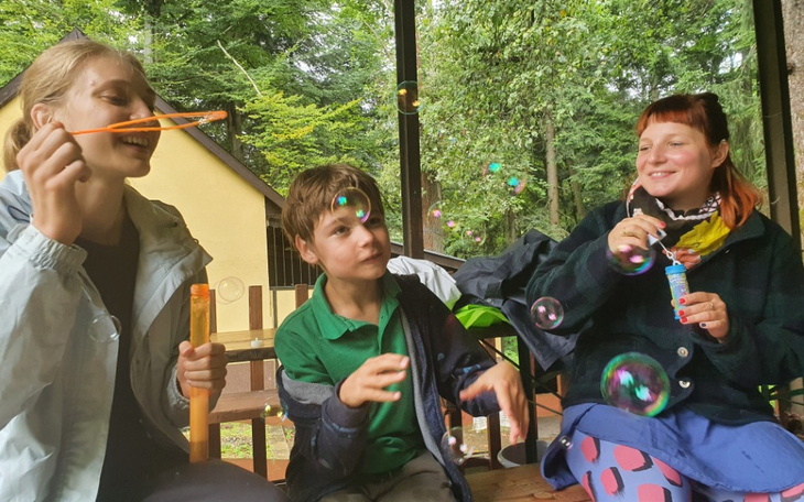 Dzieci bawią się bańkami mydlanymi w lesie.