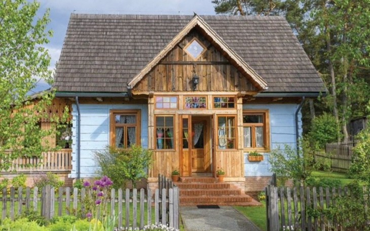 Drewniany dom w stylu wiejskim otoczony zielenią.