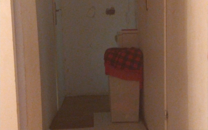 Pusty korytarz z widocznym meblem na końcu.