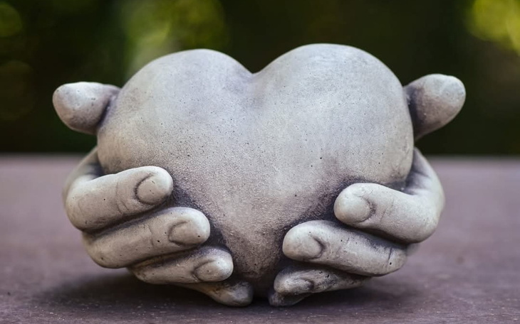 Ręce trzymające serce z betonu, symbol miłości.