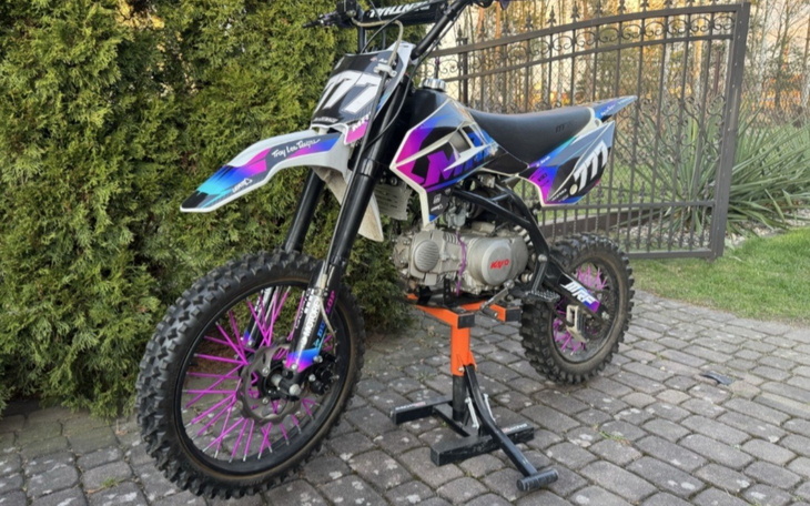 Motocykl terenowy na podjeździe przed domem.