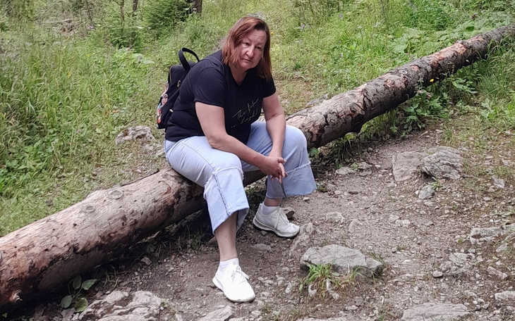 Kobieta odpoczywająca na pniu drzewa w lesie.