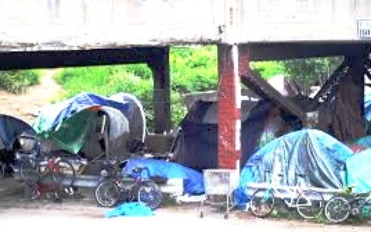 Obozowisko z namiotami pod mostem, z rowerami w tle.