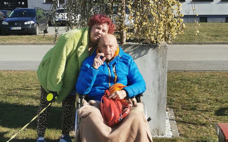 Kobieta z czerwonymi włosami i starszym mężczyzną w wózku.