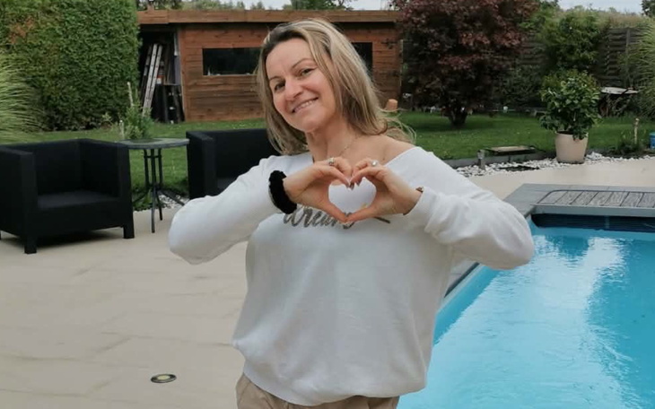 Kobieta robiąca serce rękami przy basenie.