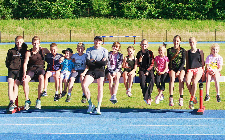 Grupa dzieci i trener na bieżni, gotowi do treningu.
