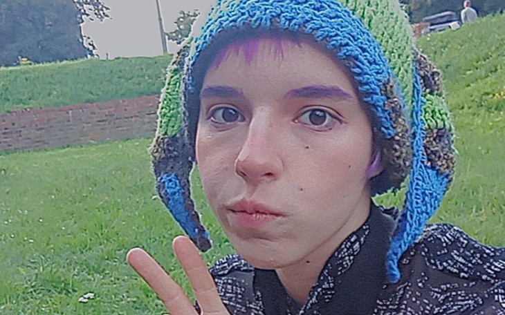 Młoda osoba w kolorowej czapce, pozująca do zdjęcia.