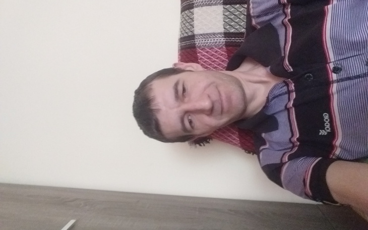 Mężczyzna uśmiechający się na tle ściany.