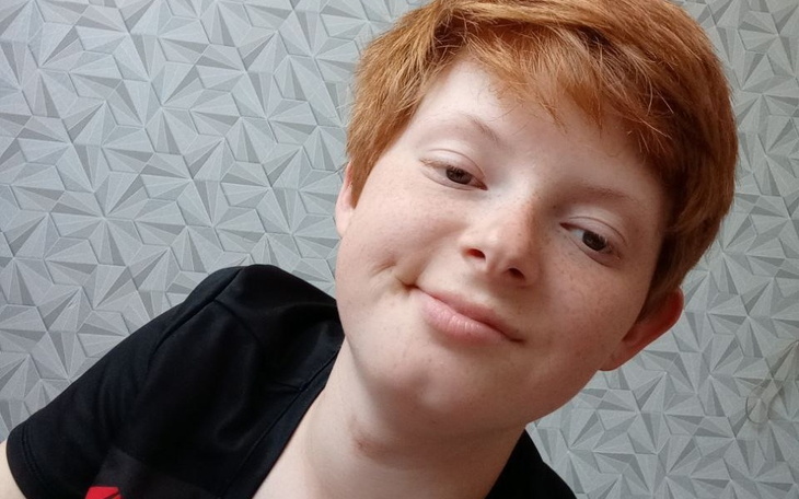 Portret uśmiechającego się chłopca z rudymi włosami.