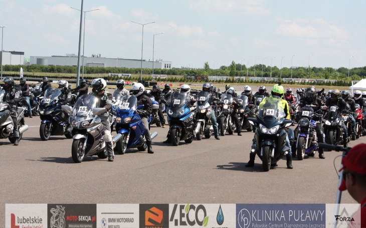 Grupa motocyklistów w kaskach na parkingu, gotowych do jazdy.