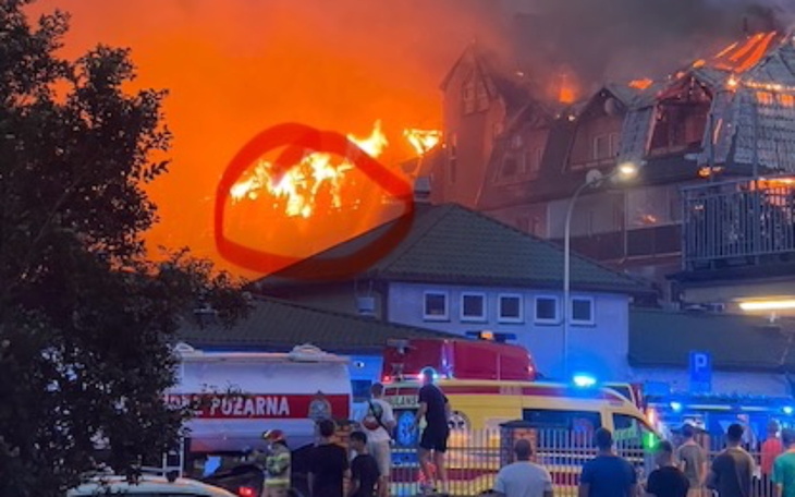 Pożar budynku, z płomieniami wydobywającymi się z dachu.