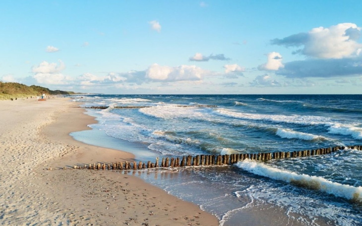 Widok na plażę z falami i chmurami na niebie.