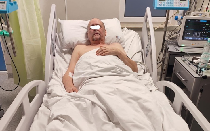Mężczyzna leżący w szpitalnym łóżku, z opatrunkiem na twarzy.