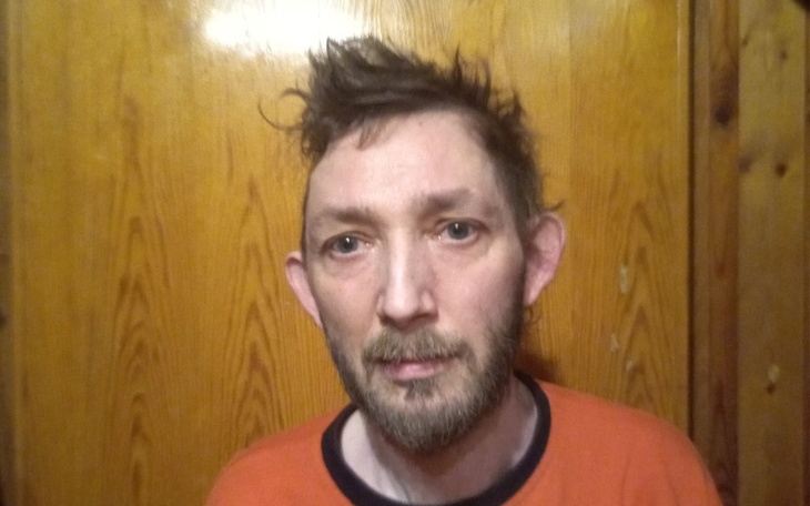 Mężczyzna z niechlujnym wyglądem, patrzący w kamerę.