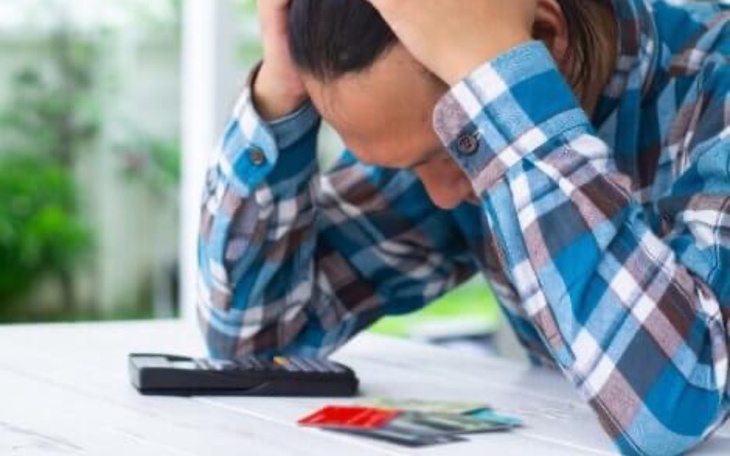 Zmartwiony mężczyzna z telefonem i kartami płatniczymi.