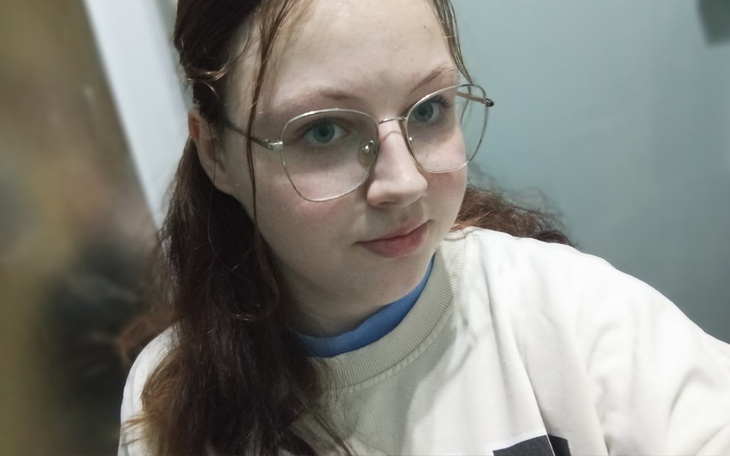 Portret dziewczyny w okularach, uśmiechającej się.