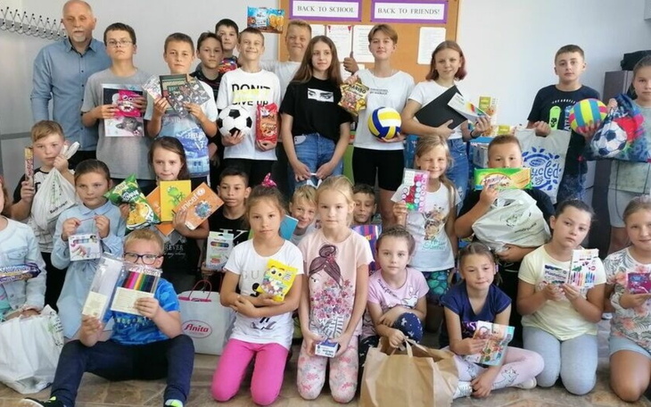 Dzieci z darami, uśmiechnięte i szczęśliwe w klasie.