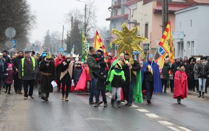Uczestnicy parady w kolorowych strojach na ulicy.