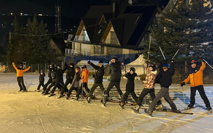 Grupa narciarzy na stoku, w radosnej pozie.