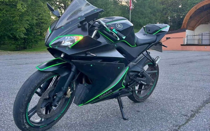 Czarny motocykl Yamaha z zielonymi akcentami, stojący na drodze.