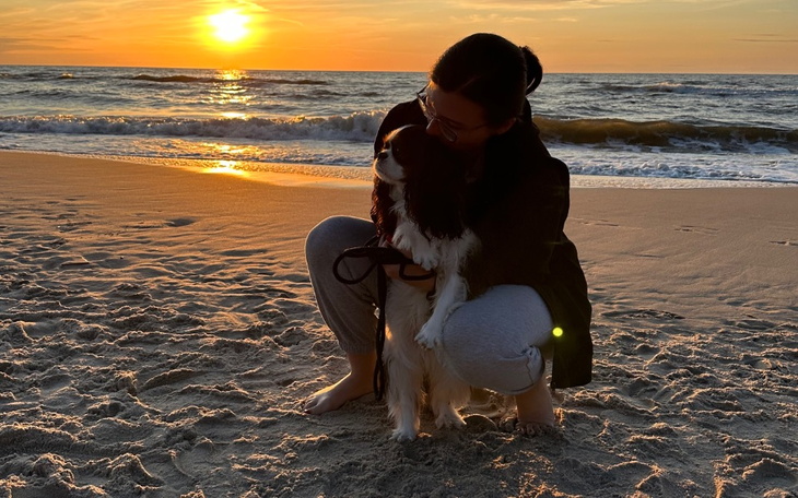 Kobieta przytulająca psa na plaży podczas zachodu słońca.