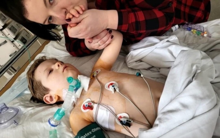 Matka całuje rękę swojego chorego syna w szpitalnym łóżku.