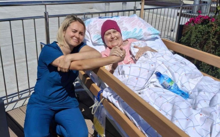 Kobieta trzymająca rękę pacjentki w łóżku szpitalnym.