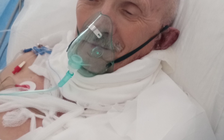 Starszy mężczyzna w szpitalu, z maską tlenową na twarzy.