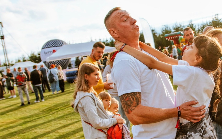 Mężczyzna bawi się z dzieckiem na festiwalu, radosna atmosfera.