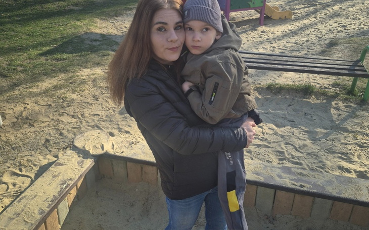 Matka z dzieckiem na placu zabaw, oboje uśmiechnięci.