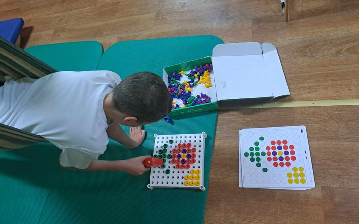 Chłopiec bawiący się kolorowymi klockami na podłodze.