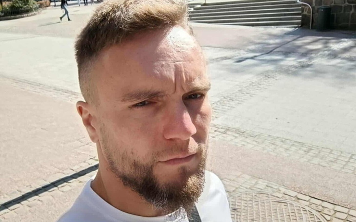 Mężczyzna z brodą na ulicy, patrzący w obiektyw.