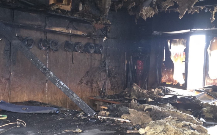 Zniszczone wnętrze po pożarze, z uszkodzonymi ścianami i sprzętem.