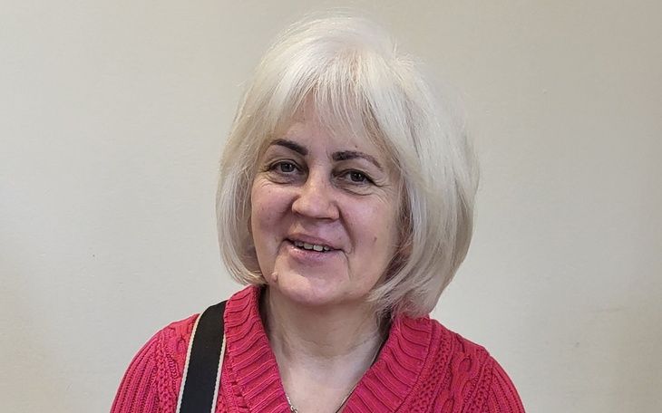 Uśmiechnięta kobieta w różowym swetrze.