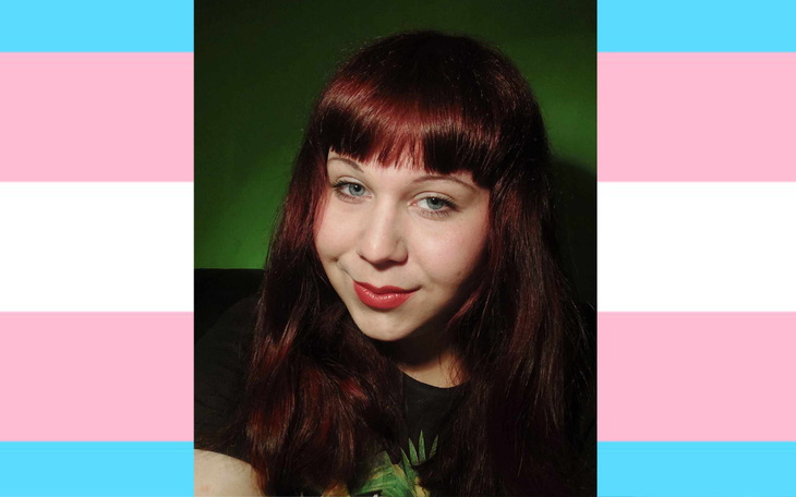 Młoda kobieta z długimi, czerwonymi włosami, uśmiechająca się do kamery.