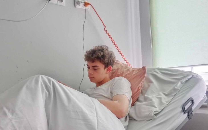 Młody mężczyzna leżący w łóżku, czytający na telefonie.