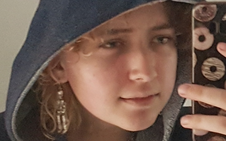 Młoda dziewczyna w kapturze z telefonem.