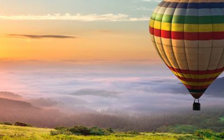 Balon na gorące powietrze unoszący się nad mglistym krajobrazem.