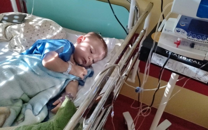 Mały chłopiec śpiący w szpitalnym łóżku, otulony kocem.