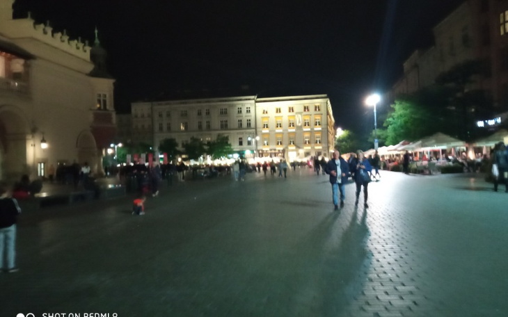 Nocny widok na rynek, z ludźmi spacerującymi po ulicy.