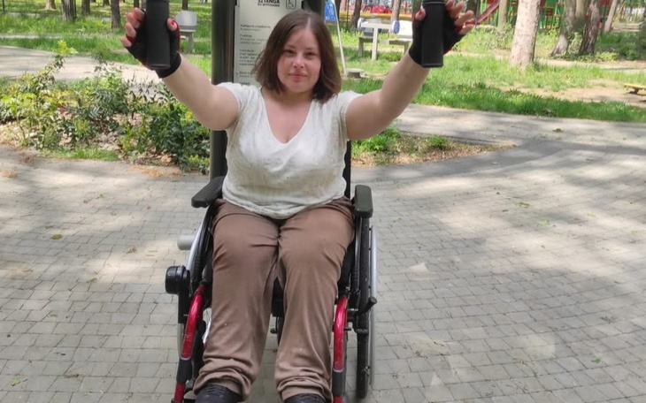 Kobieta w wózku inwalidzkim ćwiczy z uchwytami.